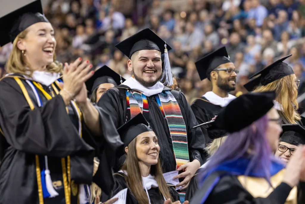 Students smiling and clapping at Commencement